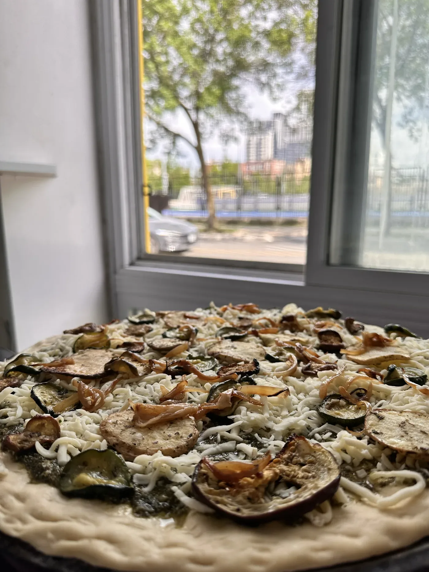 A Rainbow Valley pizza before baking: zucchini, eggplant, caramelised onion and potato on pesto